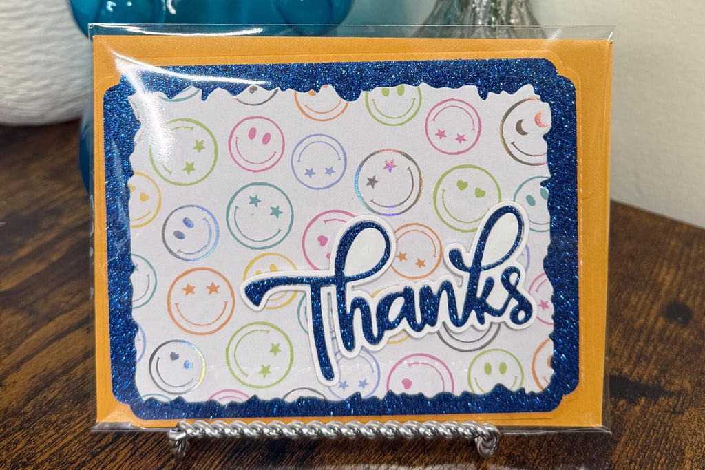 Blue gummy bear with a 'Thanks' card and flowers on a wooden surface