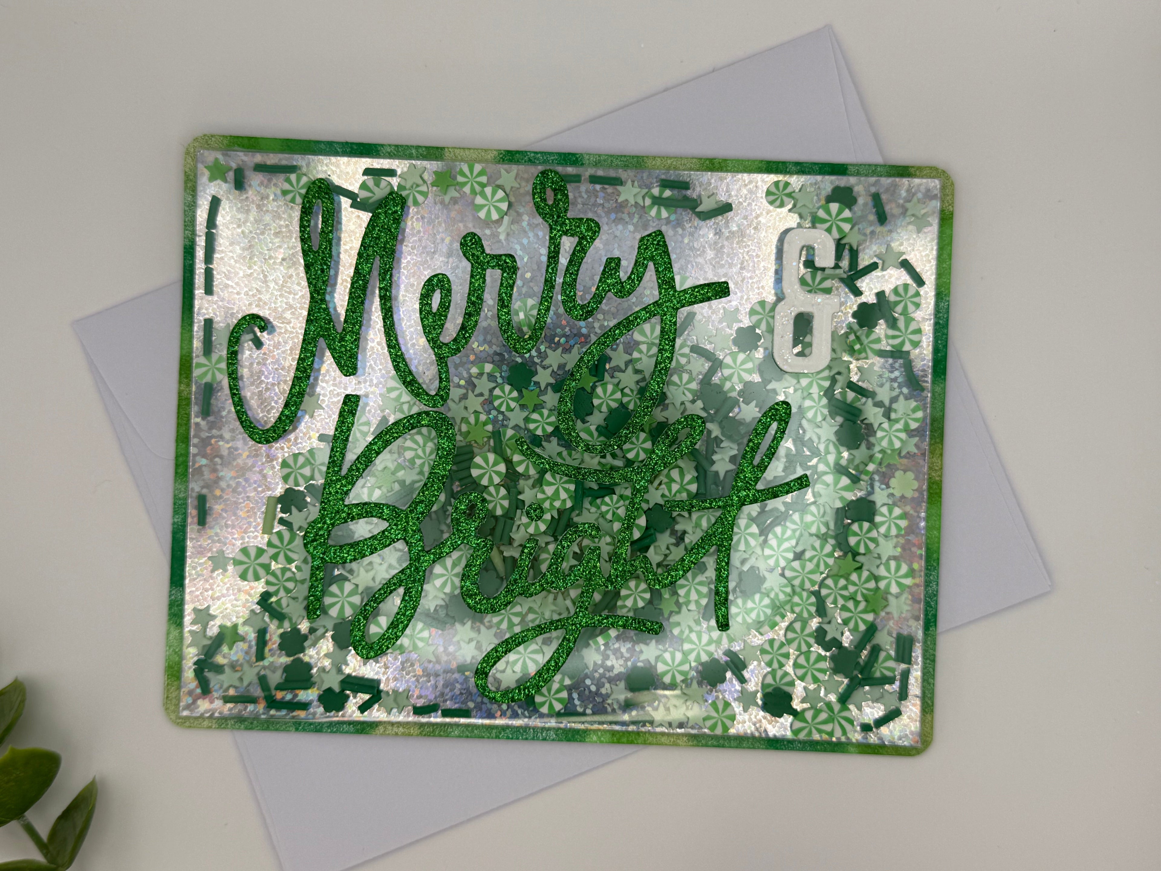 Greeting card with 'Merry & Bright' text on a textured green and silver background