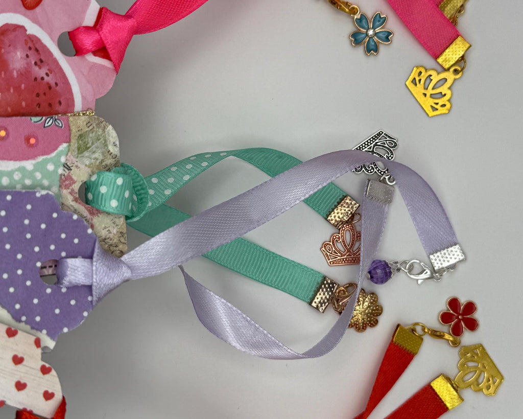 Colorful ribbon bookmarks with various charms on a light gray background
