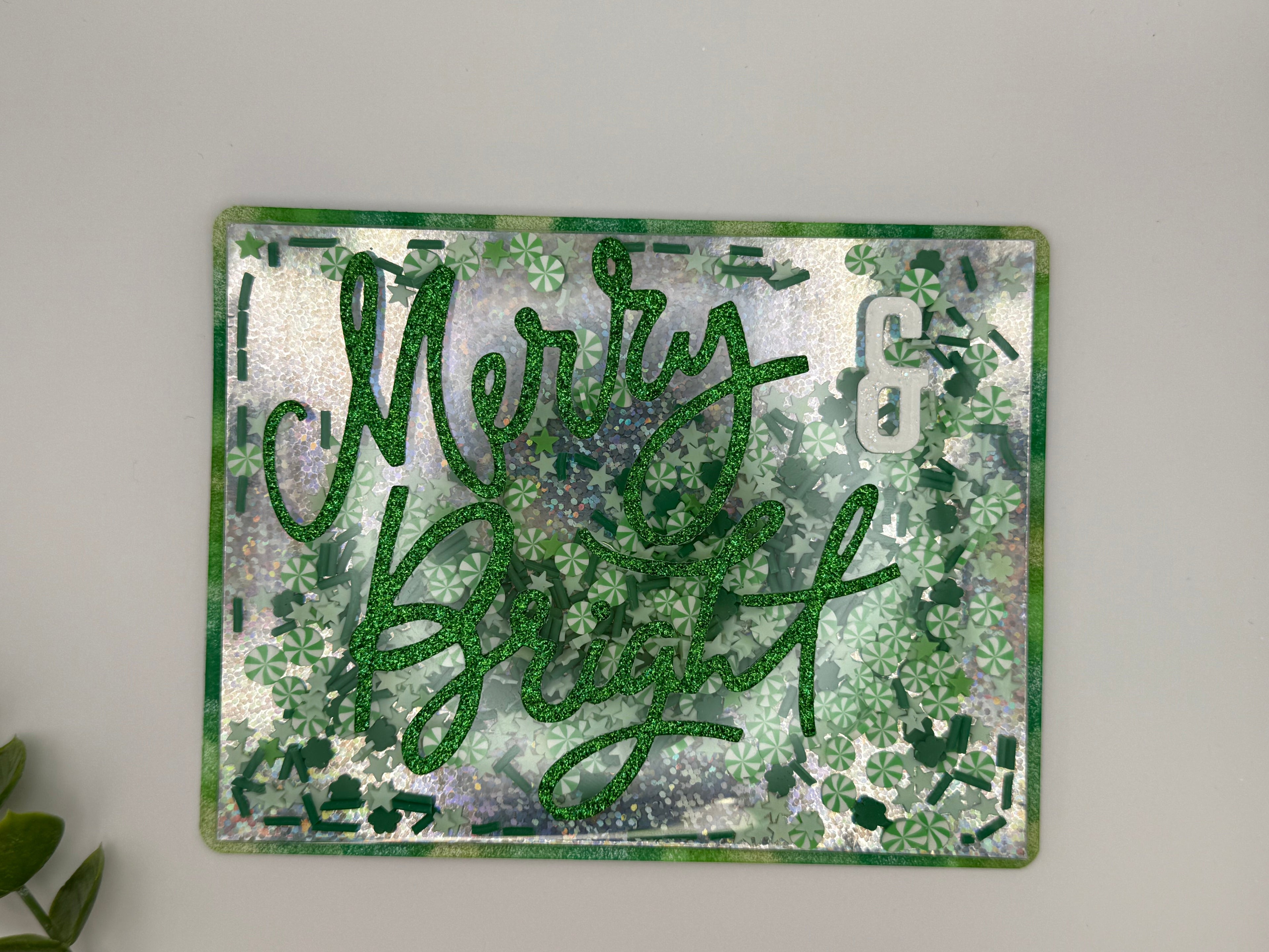 Decorative sign with 'Merry & Bright' text on a sparkly background