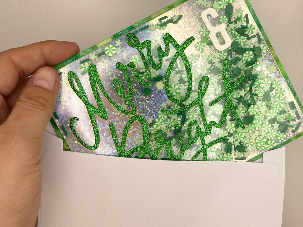 Hand holding a card with 'Merry & Bright' text and decorative patterns.