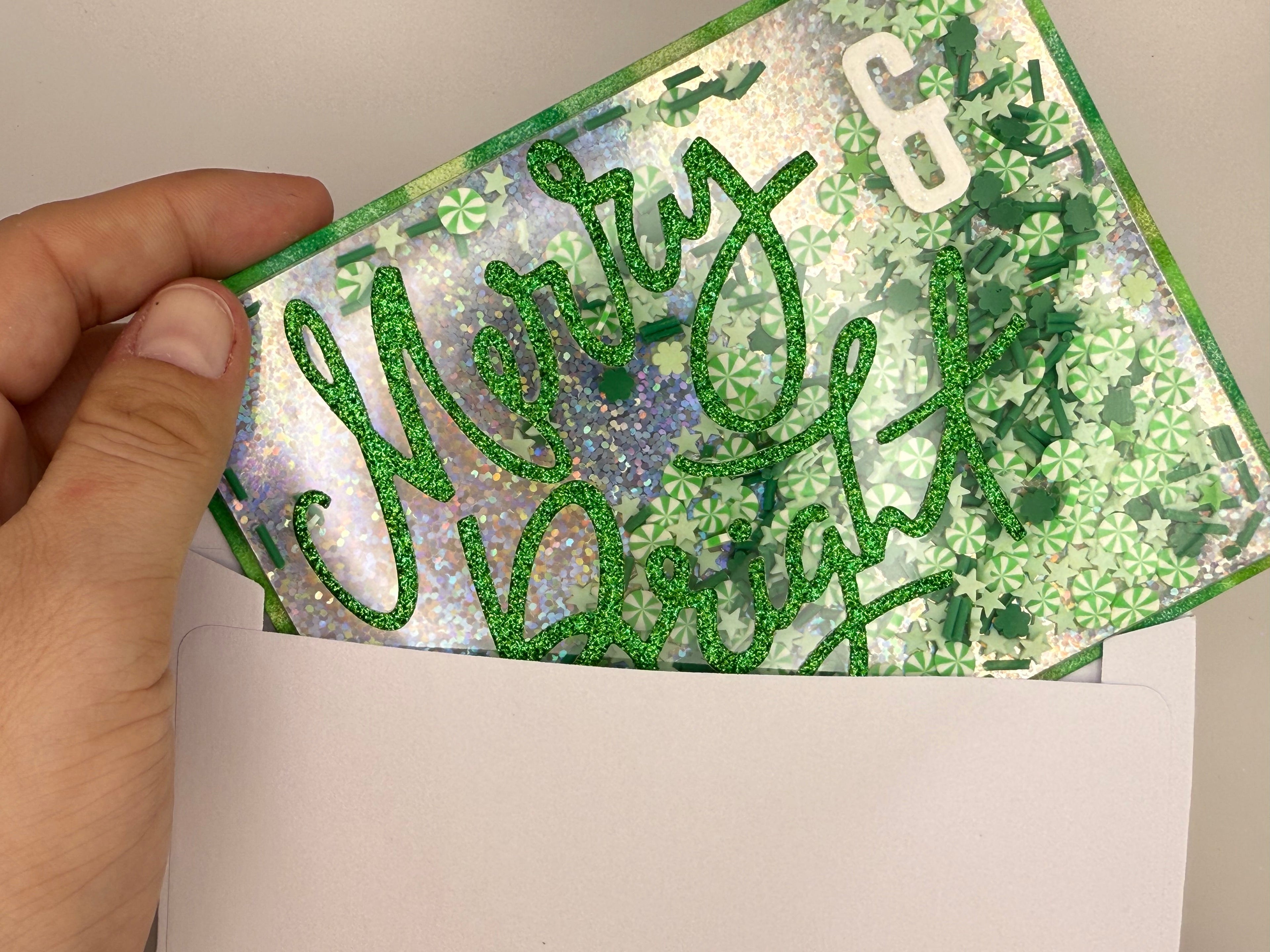 Hand holding a card with 'Merry & Bright' text and decorative patterns.