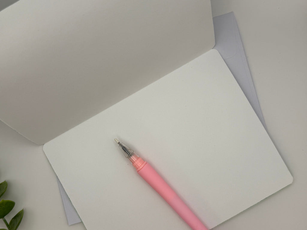 Pink pen on a white notebook with a gray background
