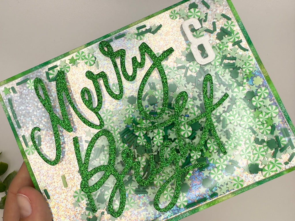 Card with 'Merry & Bright' text in green glitter on a patterned background