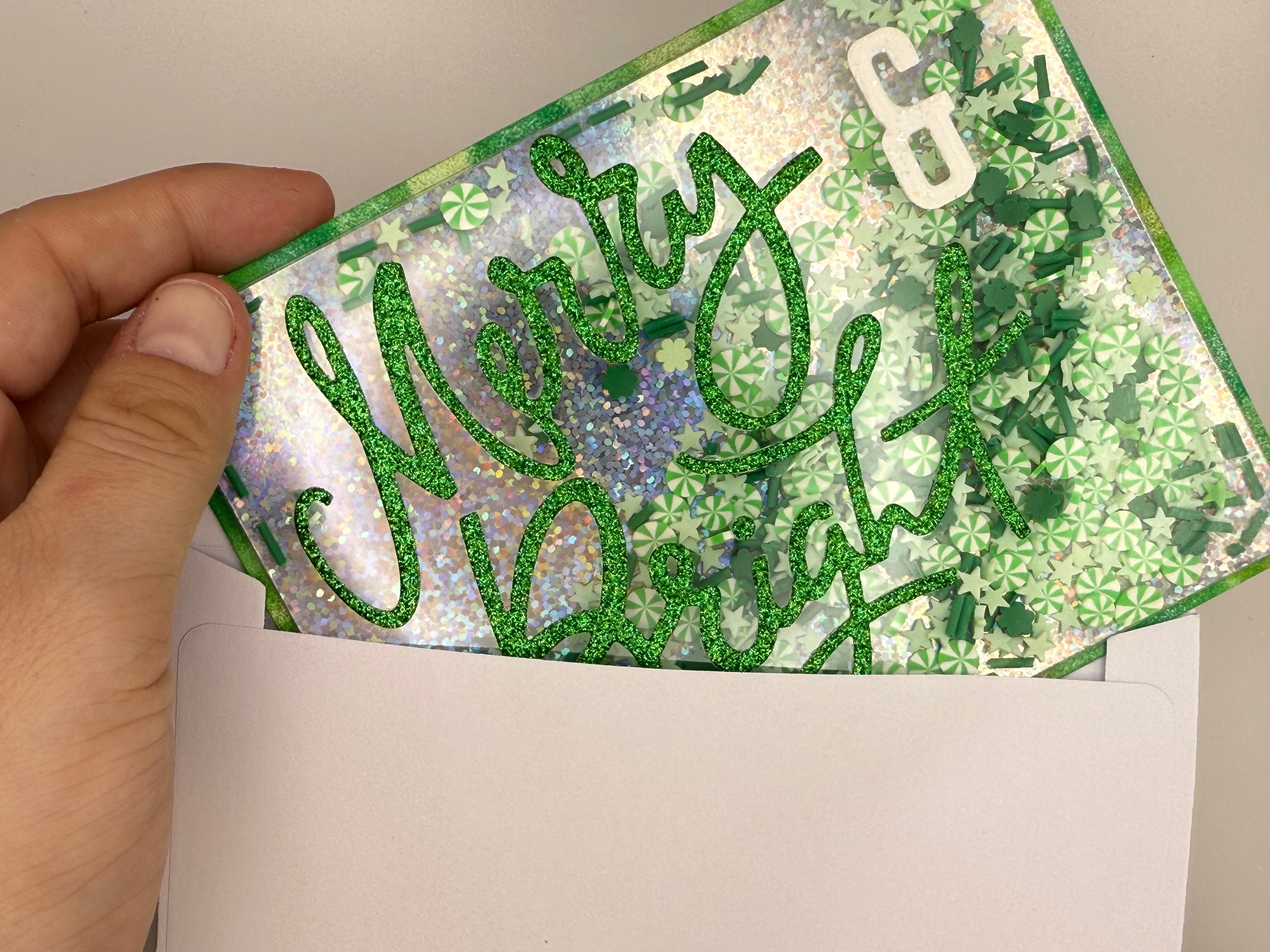 Hand holding a decorative card with 'Merry & Bright' text and floral patterns.