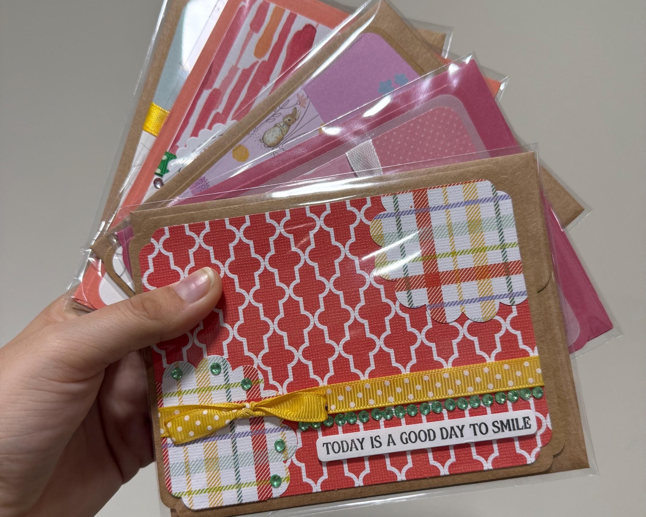 Hand holding a stack of patterned greeting cards with a visible message.