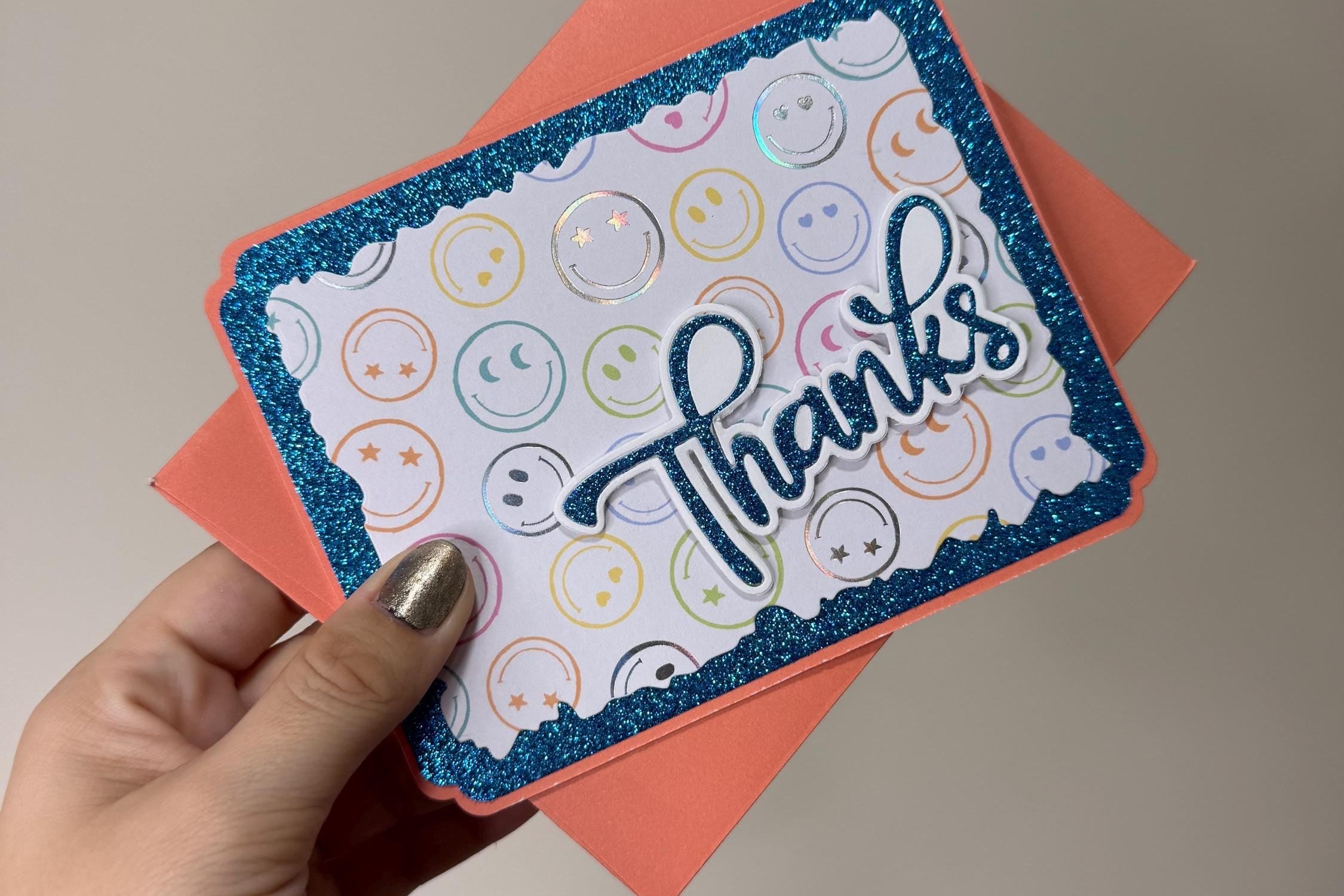 Hand holding a card with 'Thanks' on a plain background